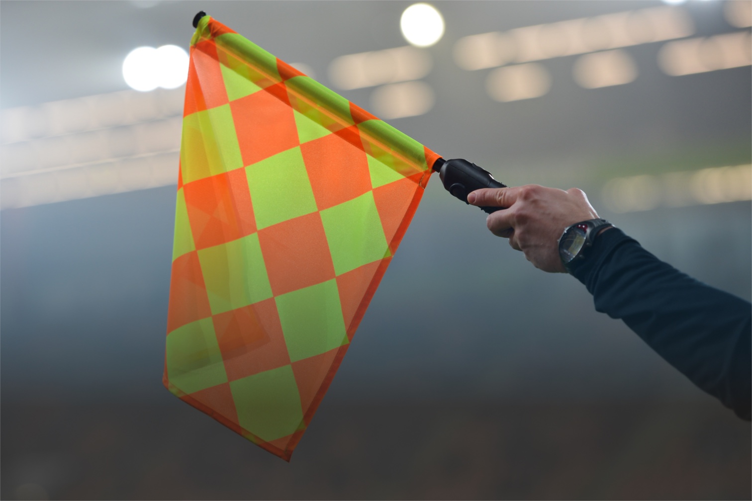 Eine gehobene Fahne eines Assistenz-Schiris in einem Fußballstadion.